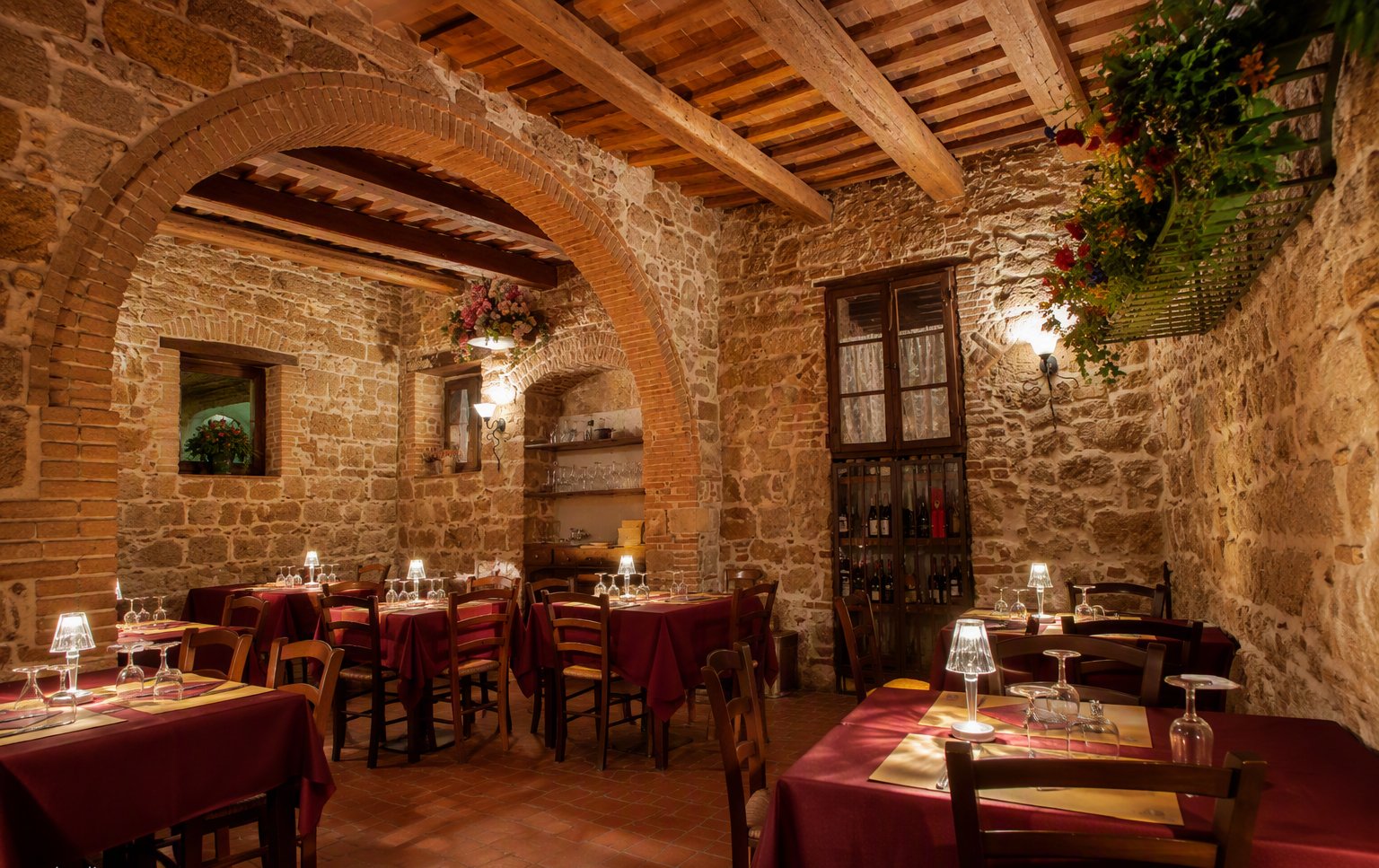 La sala in pietra con le travi di legno e le tovaglie rosse
